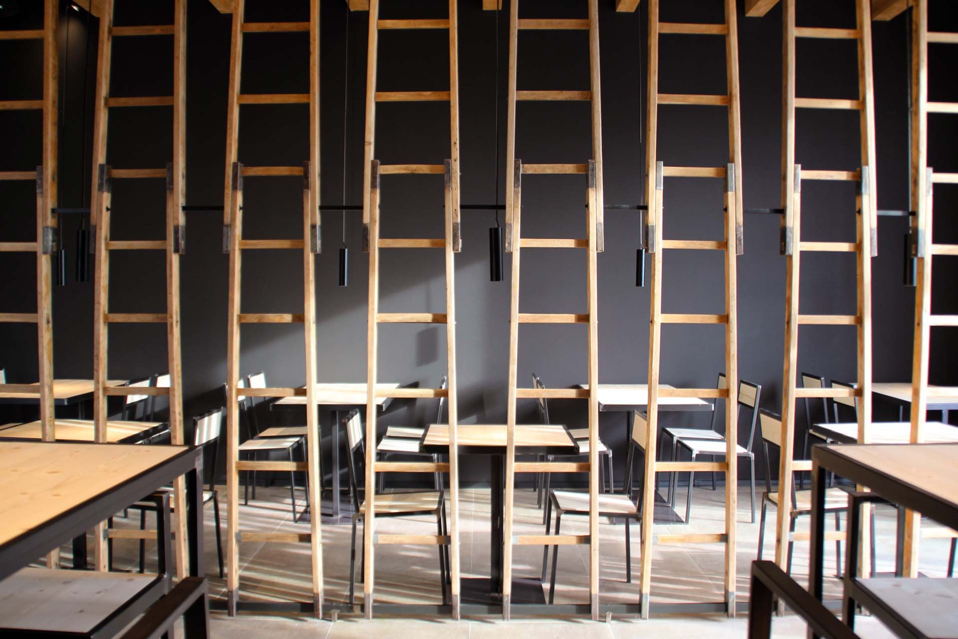 Le scale a pioli in legno appese come divisori davanti alla parete scura della taproom