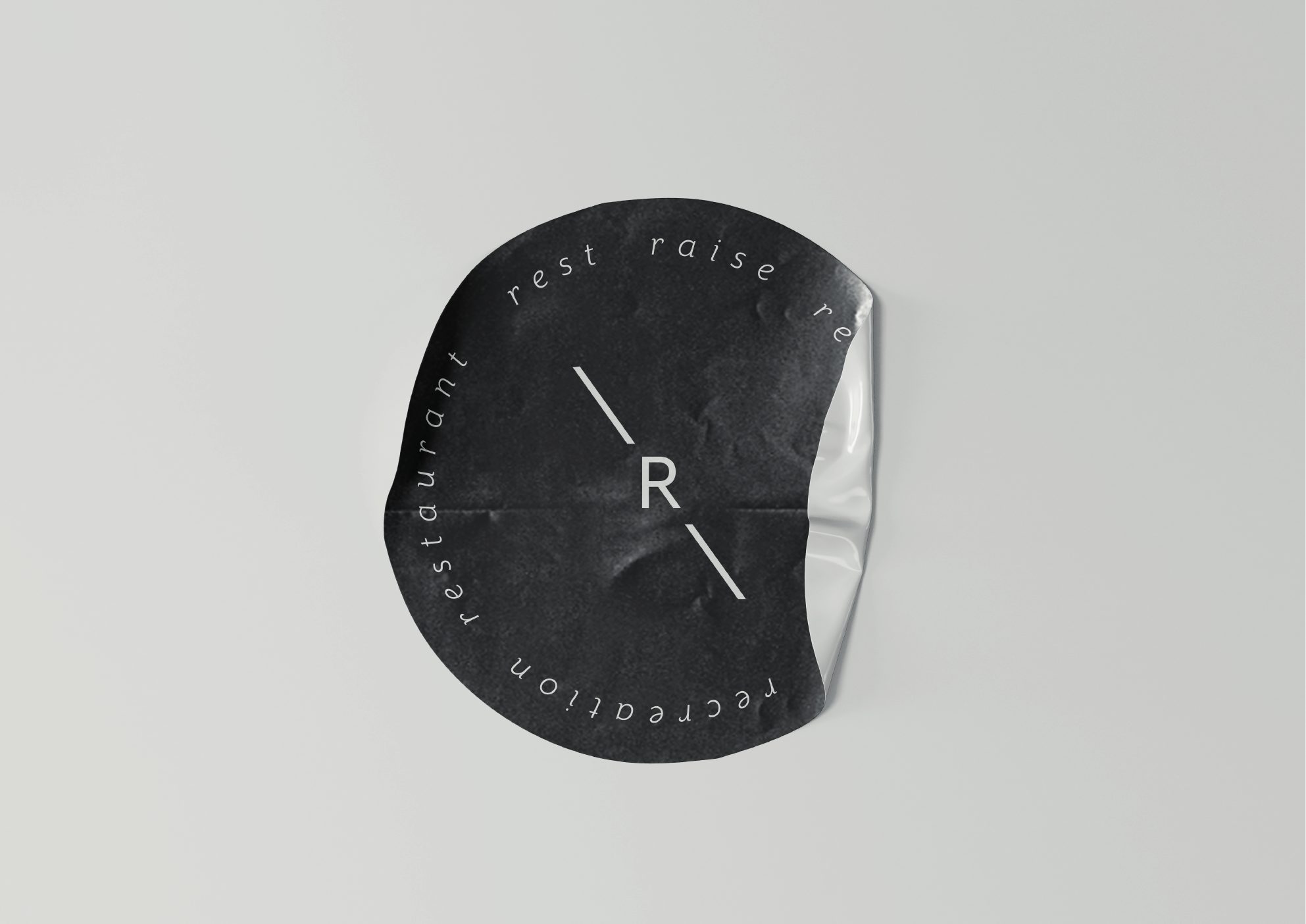 Black coaster with the R monogram and the words restaurant, rest, relax, recreation
