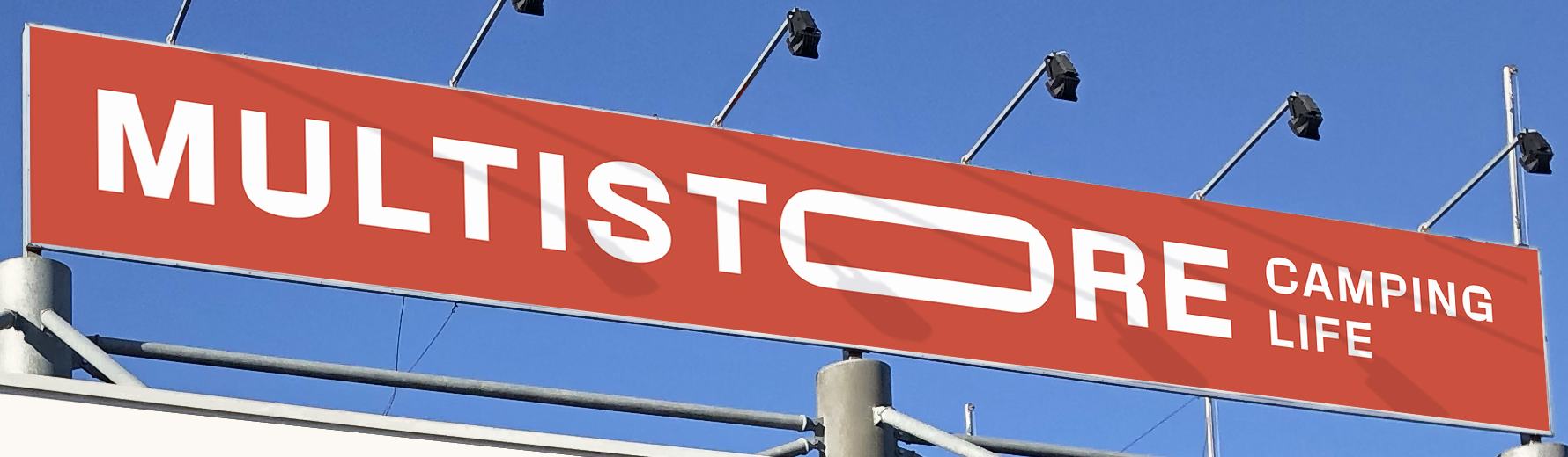 The red Multistore Camping Life sign on the roof of the shop, against the sky