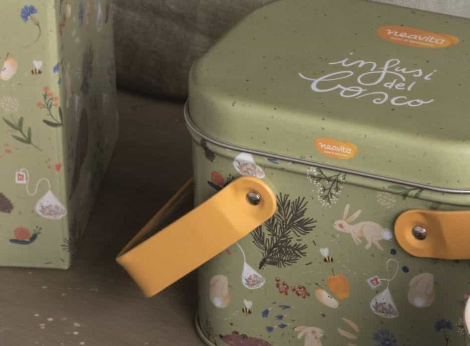 Detail of the sage green Infusi del bosco tin, with the yellow handle, a rabbit and illustrated leaves