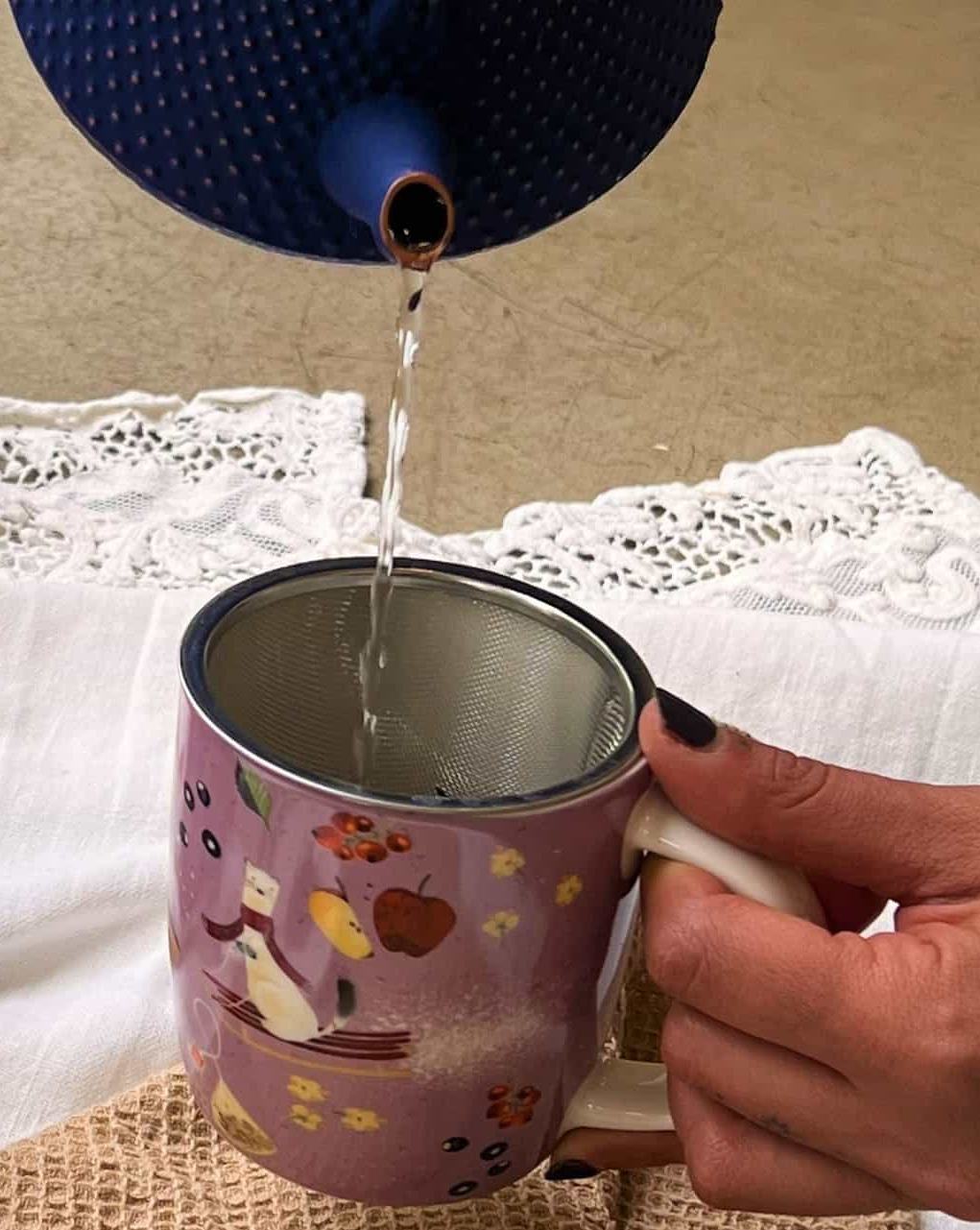 Detail of the lilac Infusi scaldacuore mug with its metal strainer, as hot water is poured in