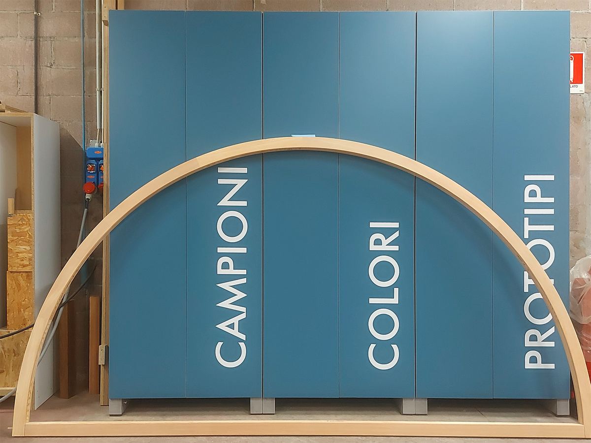 In falegnameria: un pannello con campioni, colori e prototipi accanto a un arco in legno