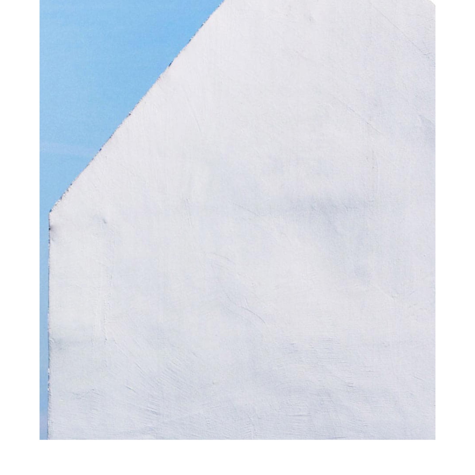 Un muro a capanna bianco de La Corte del Commiato contro il cielo azzurro