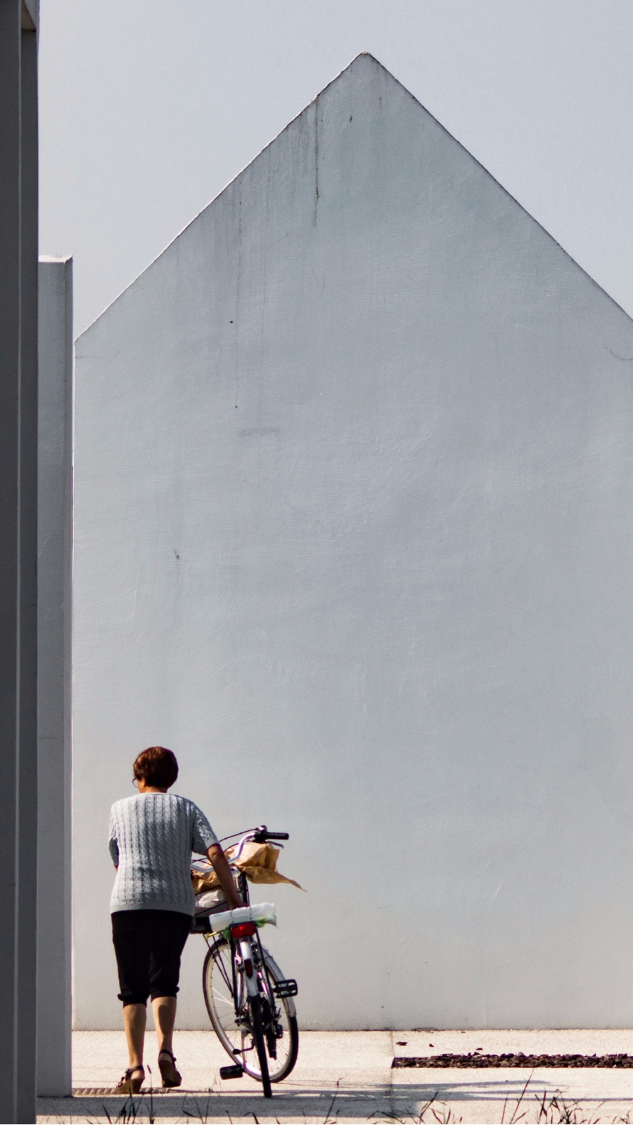 Storia Instagram: una donna con la bicicletta davanti a un muro a capanna de La Corte del Commiato