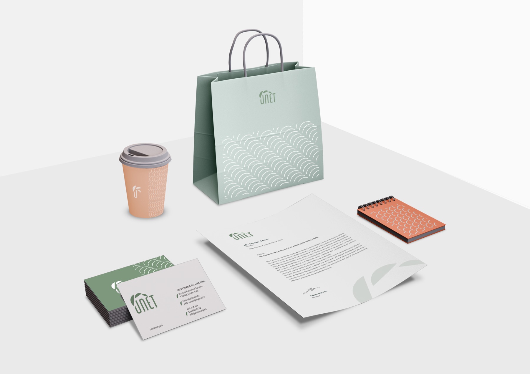 Una direzione intermedia del progetto, con palette verde acqua e salmone, su shopper, bicchiere e cancelleria